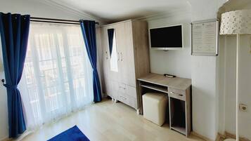 A room with a desk, a chair, a television, and a cabinet.