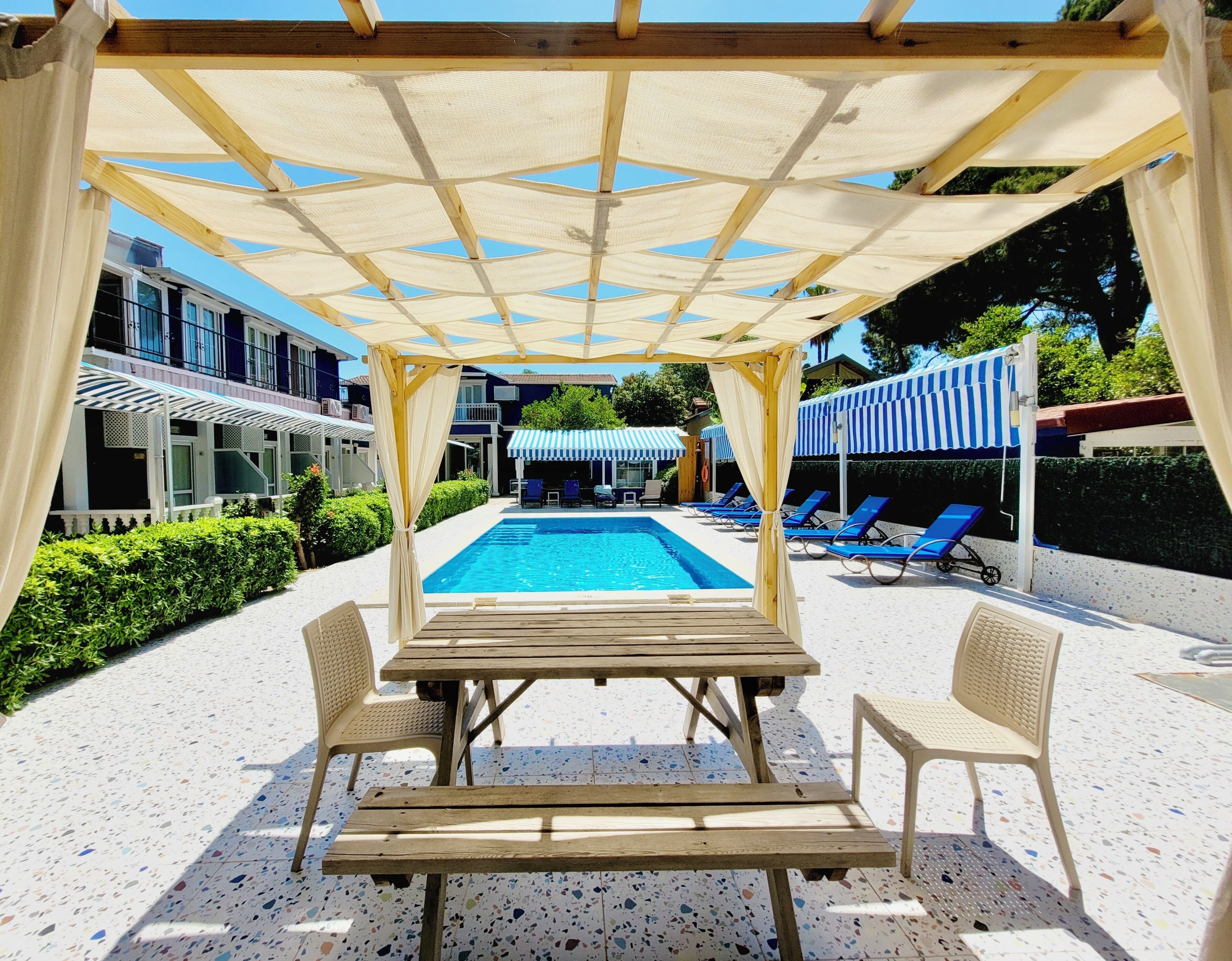 A poolside area with a covered seating area, pool, and lounge chairs.