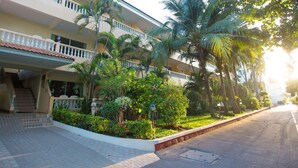 A multi-story hotel with a covered walkway, palm trees, and a well-maintained garden. - Twin Palms Resort (Pattaya)