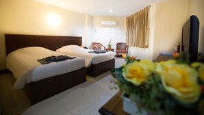 A hotel room with two beds, a desk, a chair, a TV, and a window with curtains. - Twin Palms Resort (Pattaya)