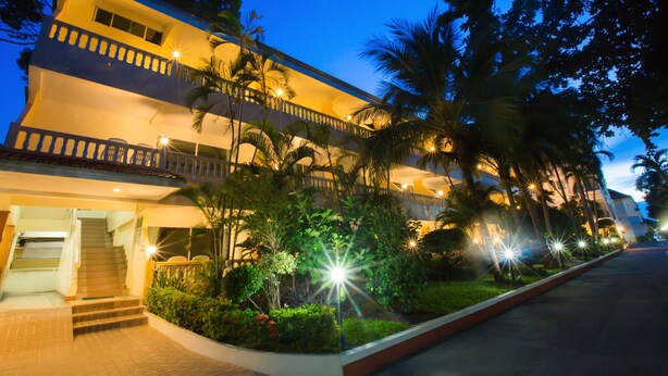 A multi-story hotel with a balcony, surrounded by palm trees and well-lit pathways. - Twin Palms Resort (Pattaya)