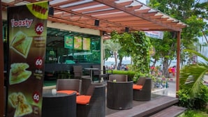 An outdoor seating area with wicker furniture and a menu board advertising Toasty sandwiches. - Twin Palms Resort (Pattaya)