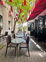 Un espace extérieur aménagé avec des tables et des chaises, un arbre et des lanternes rouges.