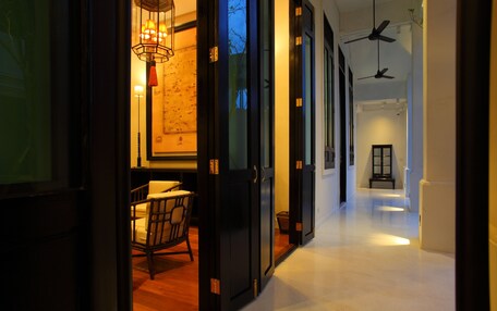 A hallway with a wooden floor, black-framed doors, and a hanging light fixture.