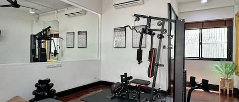 A gym with exercise equipment, a bench, and a ceiling fan.