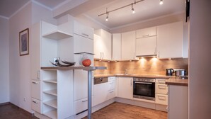 A modern kitchen with white cabinetry, a wooden countertop, and a built-in oven. - Aparthotel Andreas Hofer (Kufstein)