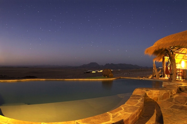 Una piscina al aire libre, sillones reclinables de piscina
