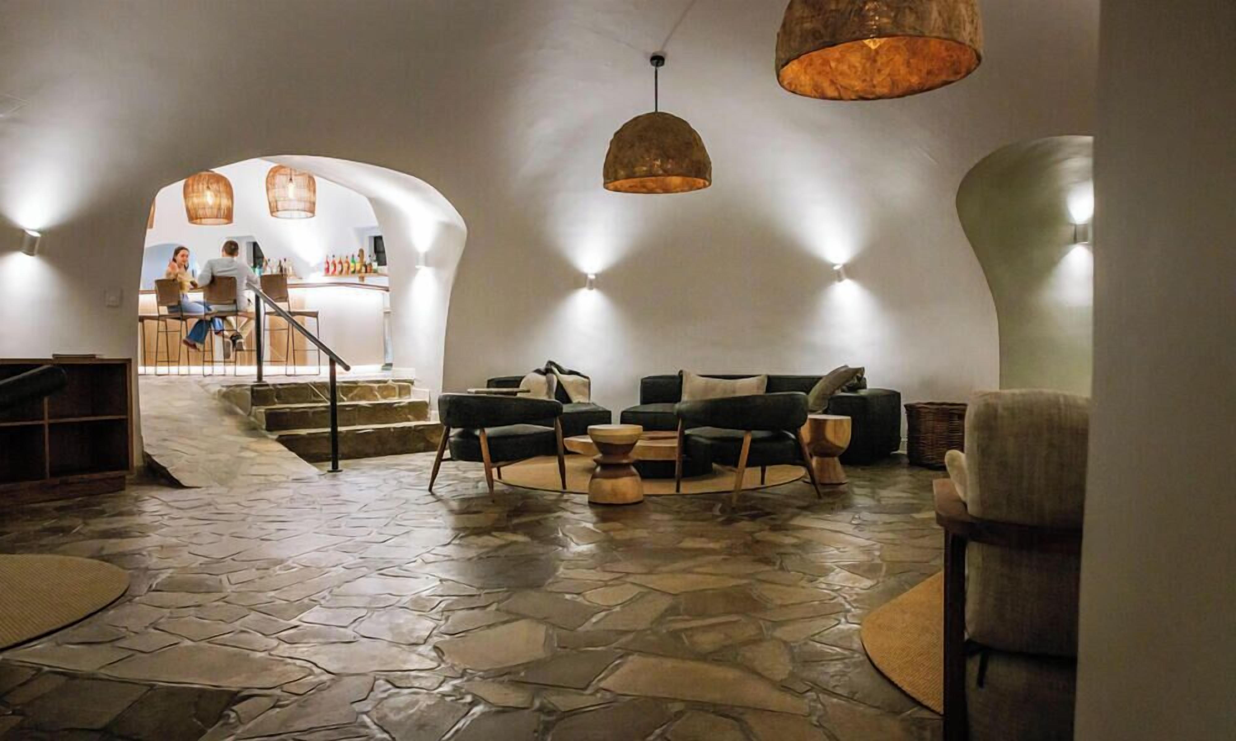 A modern interior with a stone floor, a bar area, and seating with a round coffee table.