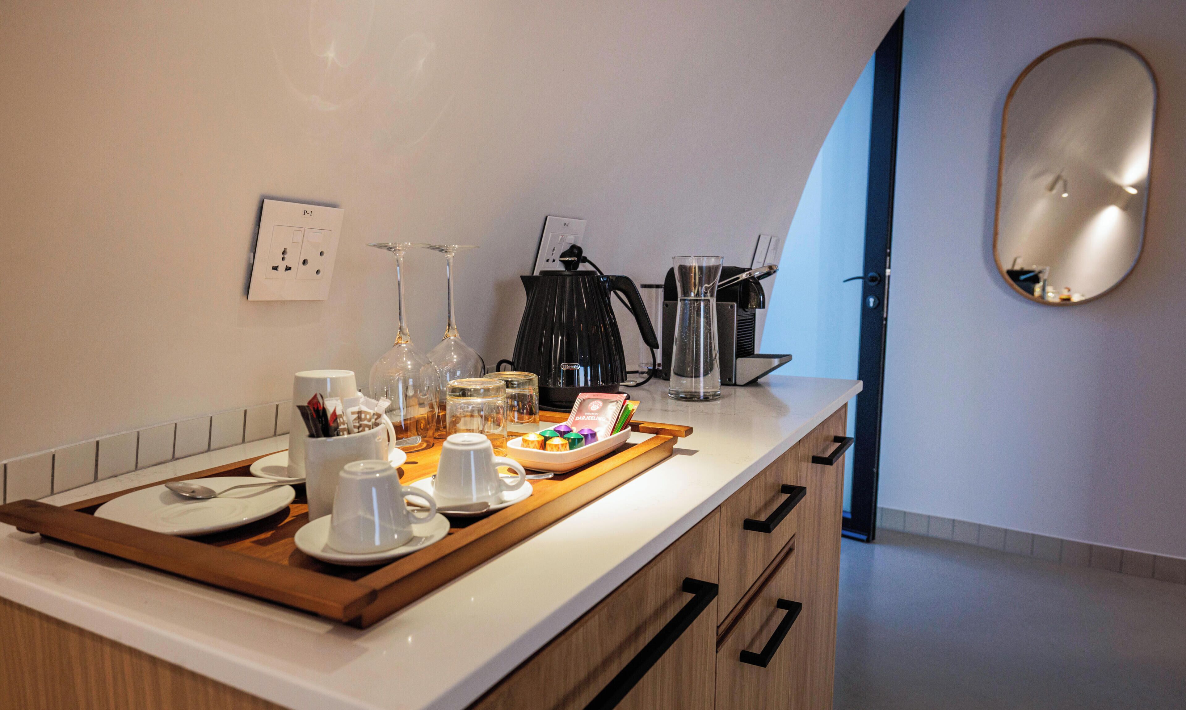Uma cozinha moderna com um espaço para café, incluindo um tabuleiro com chávenas e uma máquina de café.