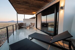 Un espace extérieur moderne, aménagé avec des fauteuils et des chaises en osier, offrant une vue sur un paysage désertique.