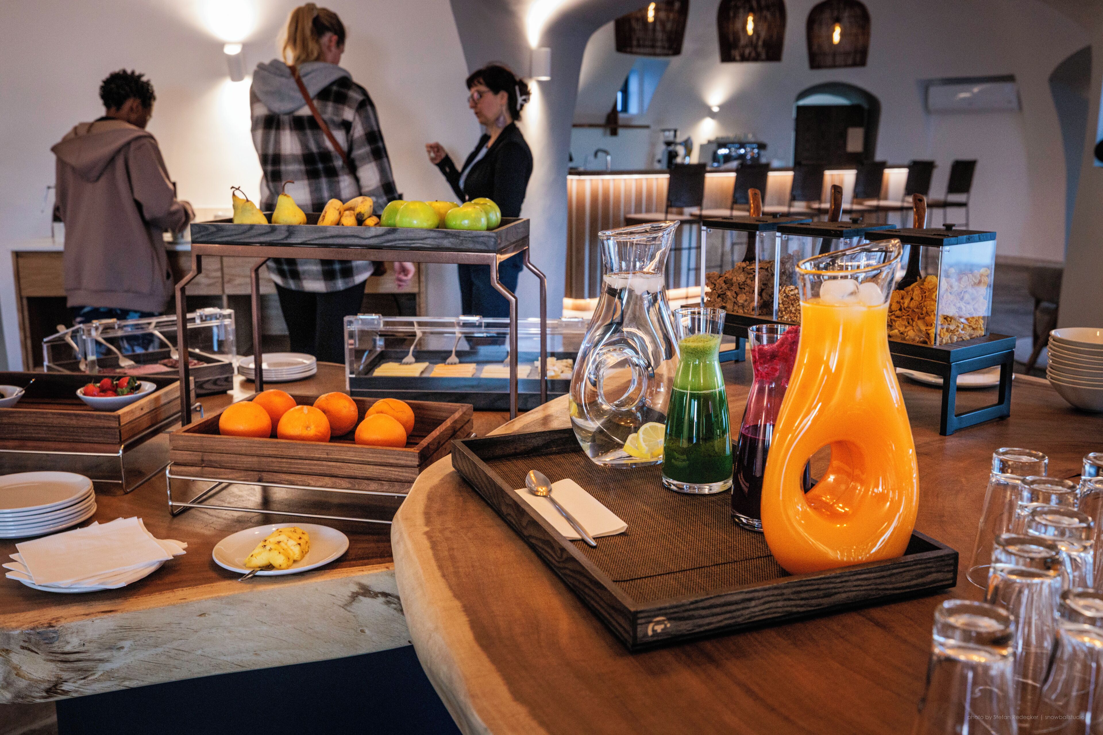Una mesa de buffet con frutas, bebidas y alimentos para el desayuno.