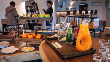 Una mesa de buffet con frutas, bebidas y alimentos para el desayuno.