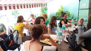 Un grup de persones dinuant en un restaurant a l'aire lliure amb taules i caires, envoltat de vegetació.