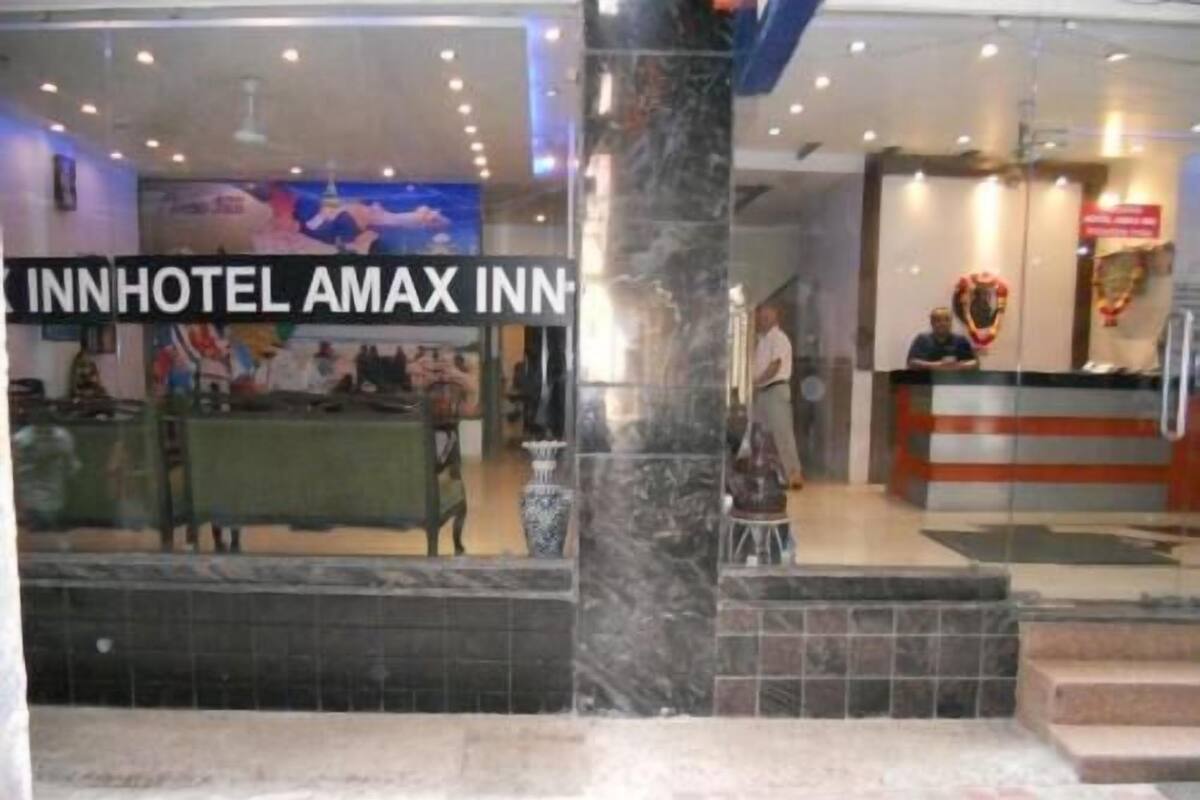 A hotel reception area with a marble column, a reception desk, and a sign for 'INNHOTEL AMAX INN'.