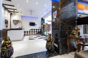 A lobby with marble flooring, a reception desk, and decorative statues. - Hotel Amax Inn (New Delhi)