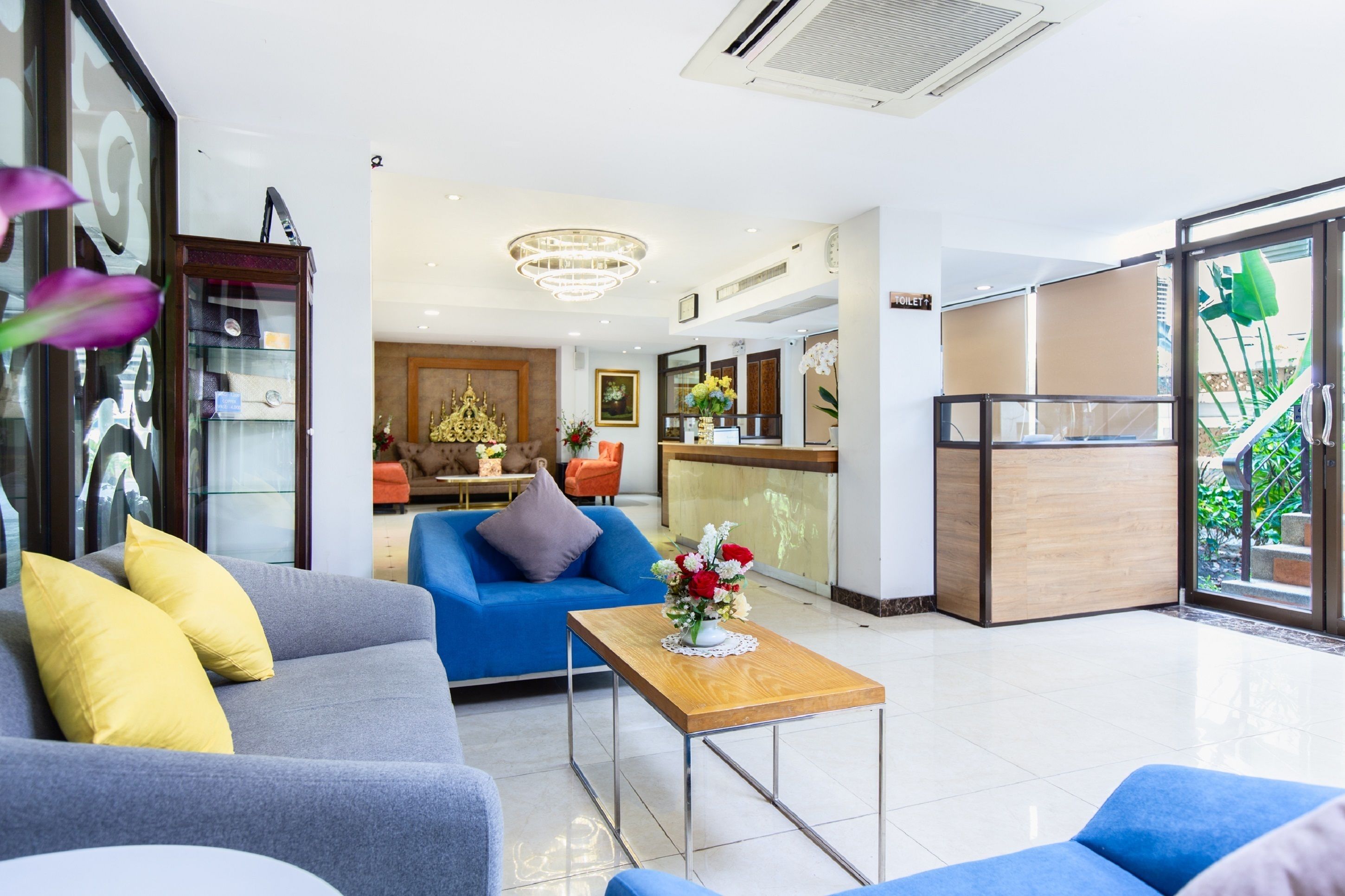 A modern hotel lobby with a blue sofa, a wooden coffee table, and a reception desk.