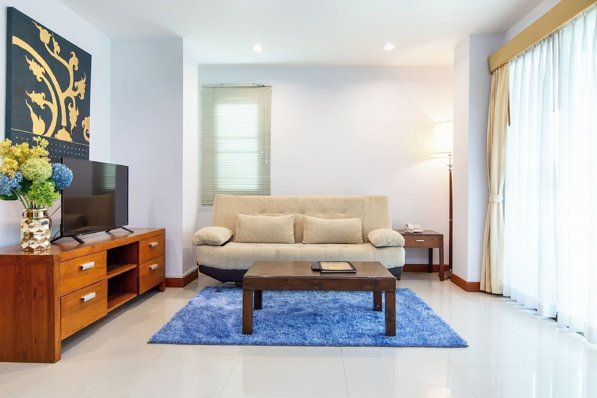 Una sala moderna con sofá, mesa de centro, televisor y un jarrón decorativo.