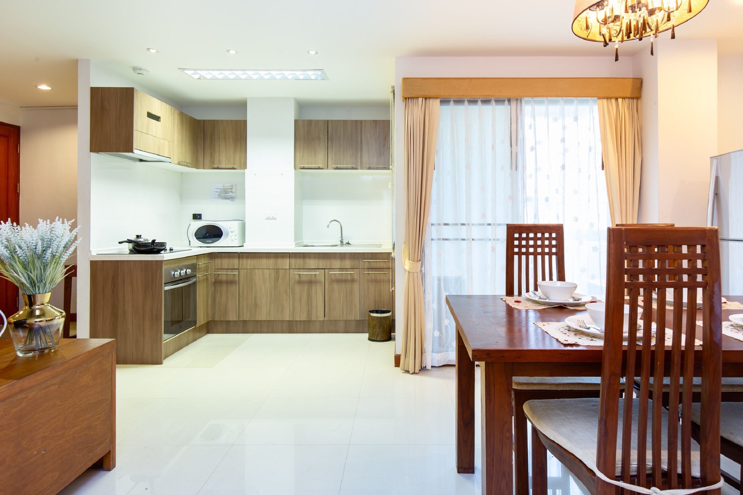 A modern kitchen with wooden cabinets, a microwave, and a dining area with a table and chairs.