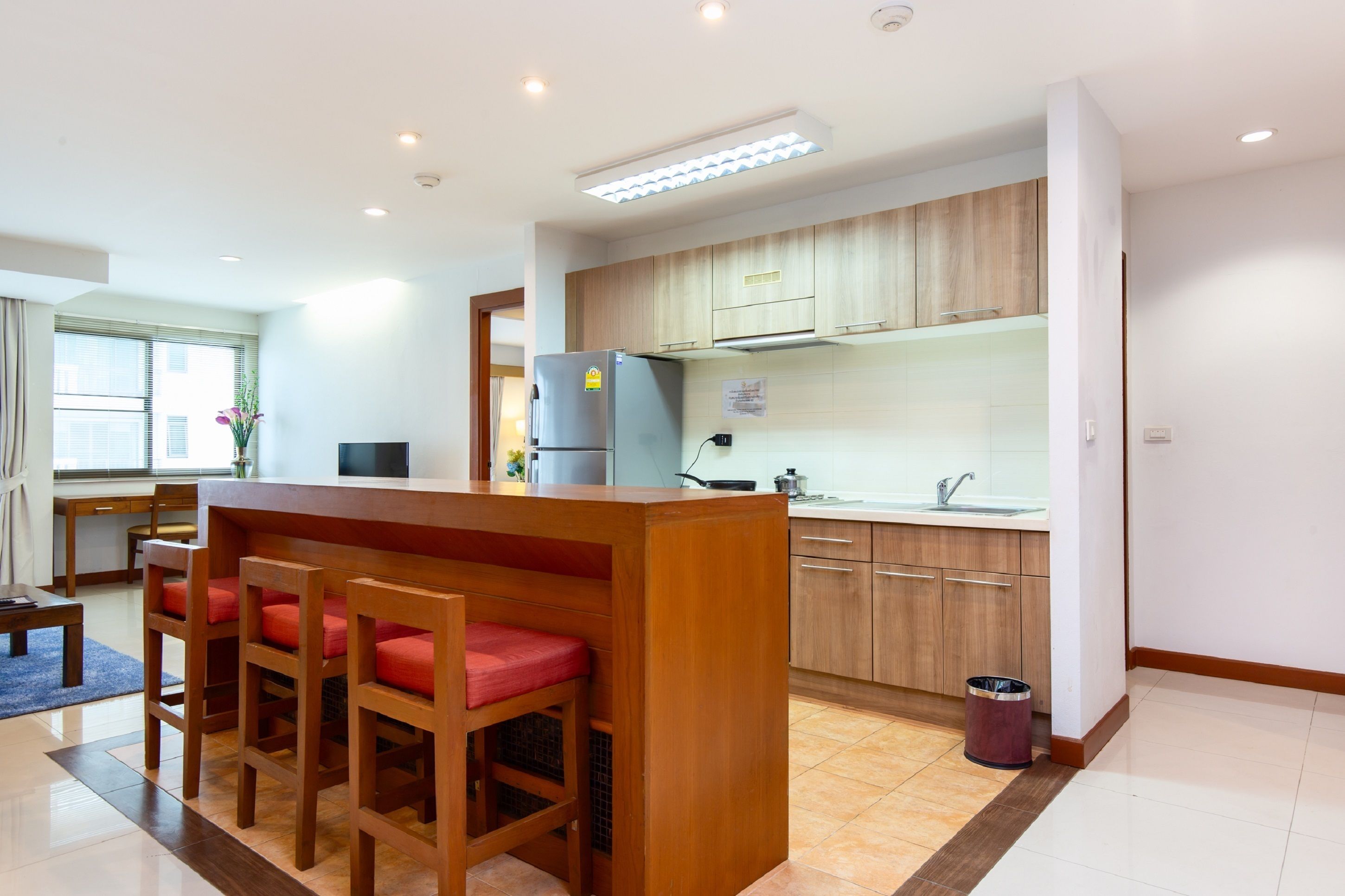 A modern kitchen with wooden cabinets, a central island with bar stools, and a built-in oven.