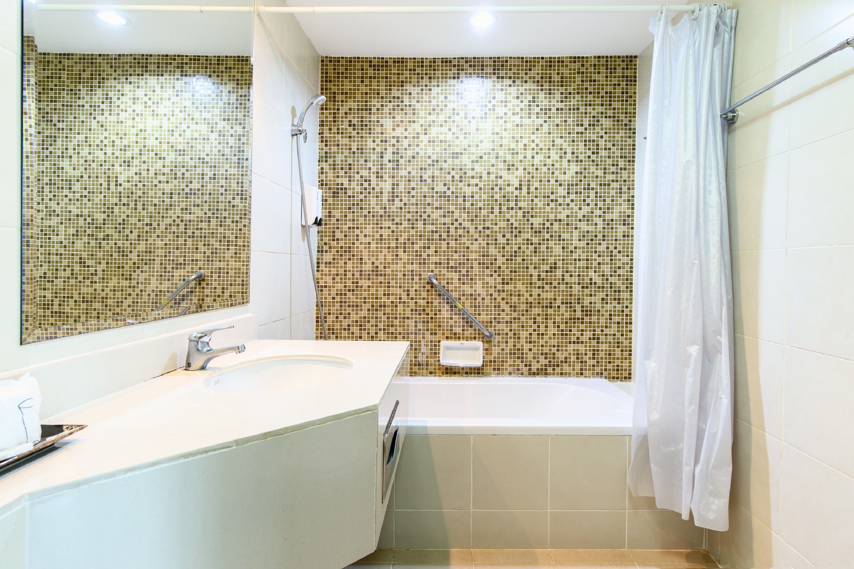 A bathroom with a white sink, a bathtub, and a shower with a mosaic tile wall.