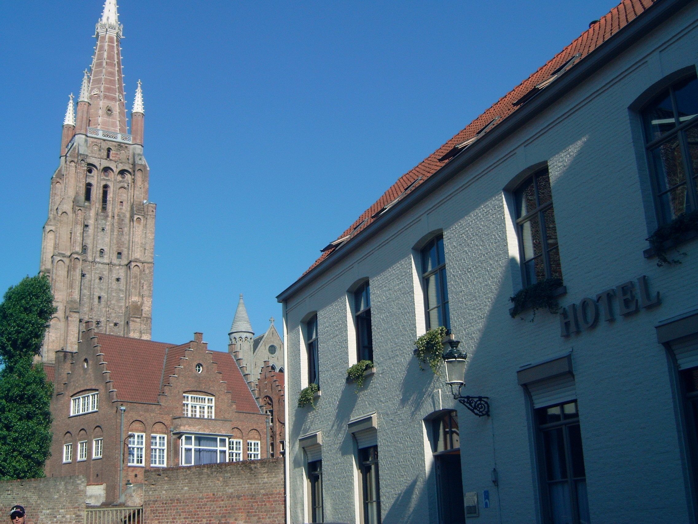 A historic building with a prominent tower, a hotel with a sign, and a clear blue sky.