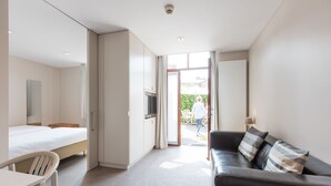 Ett modernt hotellrum med en säng, ett skrivbord, en soffa och en TV.