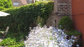 En innergård med ett stort blomsterland, en tegelmur och en byggnad med ett torn i bakgrunden.