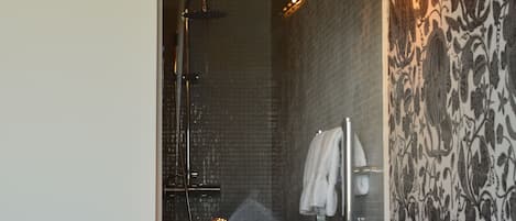 A hotel room with a bed, a shower, and a bathroom with a towel rack.