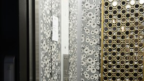A room with a patterned wallpaper, a metallic door, and a wall with circular mirrors.