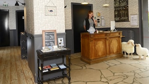 A reception area with a wooden counter, a black and white striped shirted receptionist, a bulletin board with a fish illustration, and a bulletin board with a plant illustration.