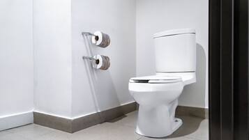A modern bathroom with a white toilet, a toilet paper holder, and a tiled floor.