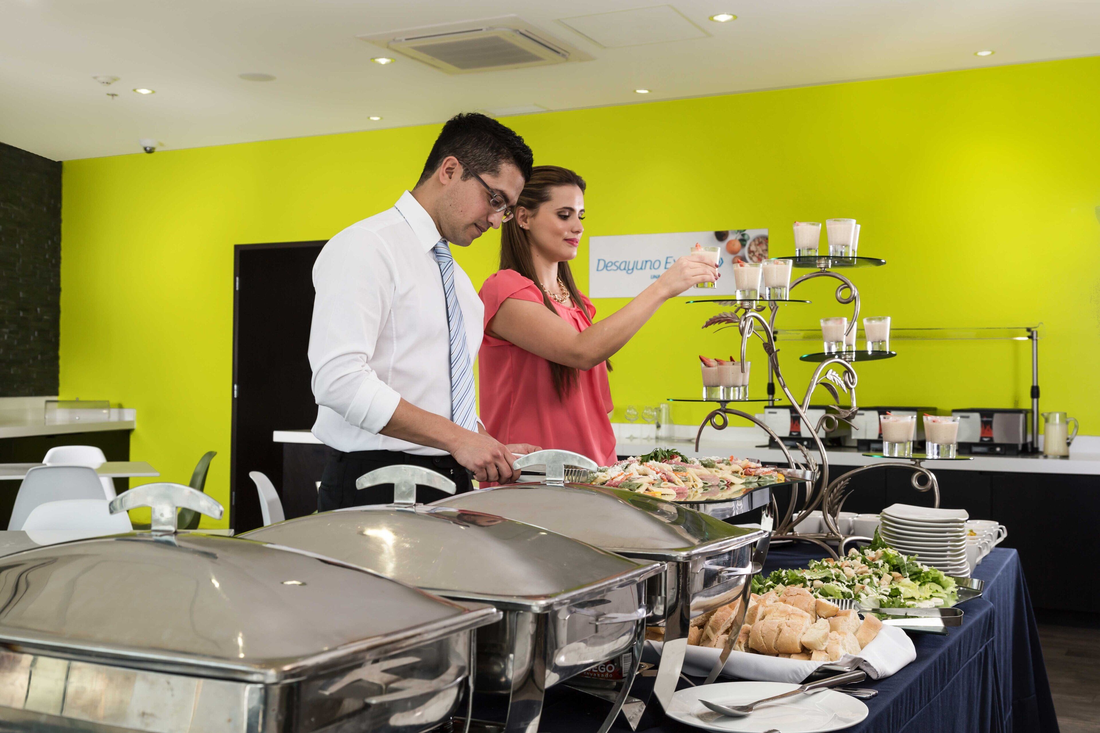 A buffet setup with various food items and a sign that reads 'Desayuno.'