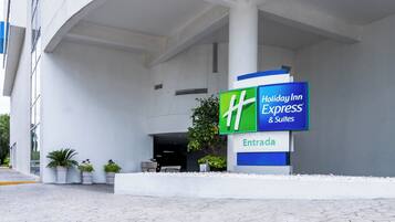 A Holiday Inn Express & Suites entrance with a clear sign, potted plants, and a modern architectural design.