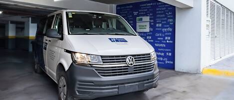 A white van parked in a parking garage with a blue exit sign above it.