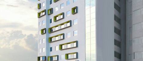 Un edificio de hotel de varios pisos con un llamativo esquema de colores verde y blanco, que presenta un diseño arquitectónico moderno con grandes ventanales y balcones.