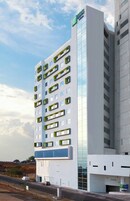Un edificio de hotel de varios pisos con un llamativo esquema de colores verde y blanco, que presenta un diseño arquitectónico moderno con grandes ventanales y balcones.