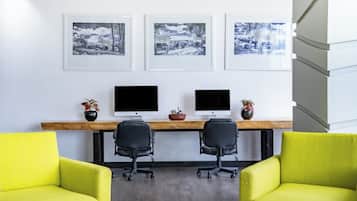 A modern office with two desks, two chairs, and three framed pictures on the wall.