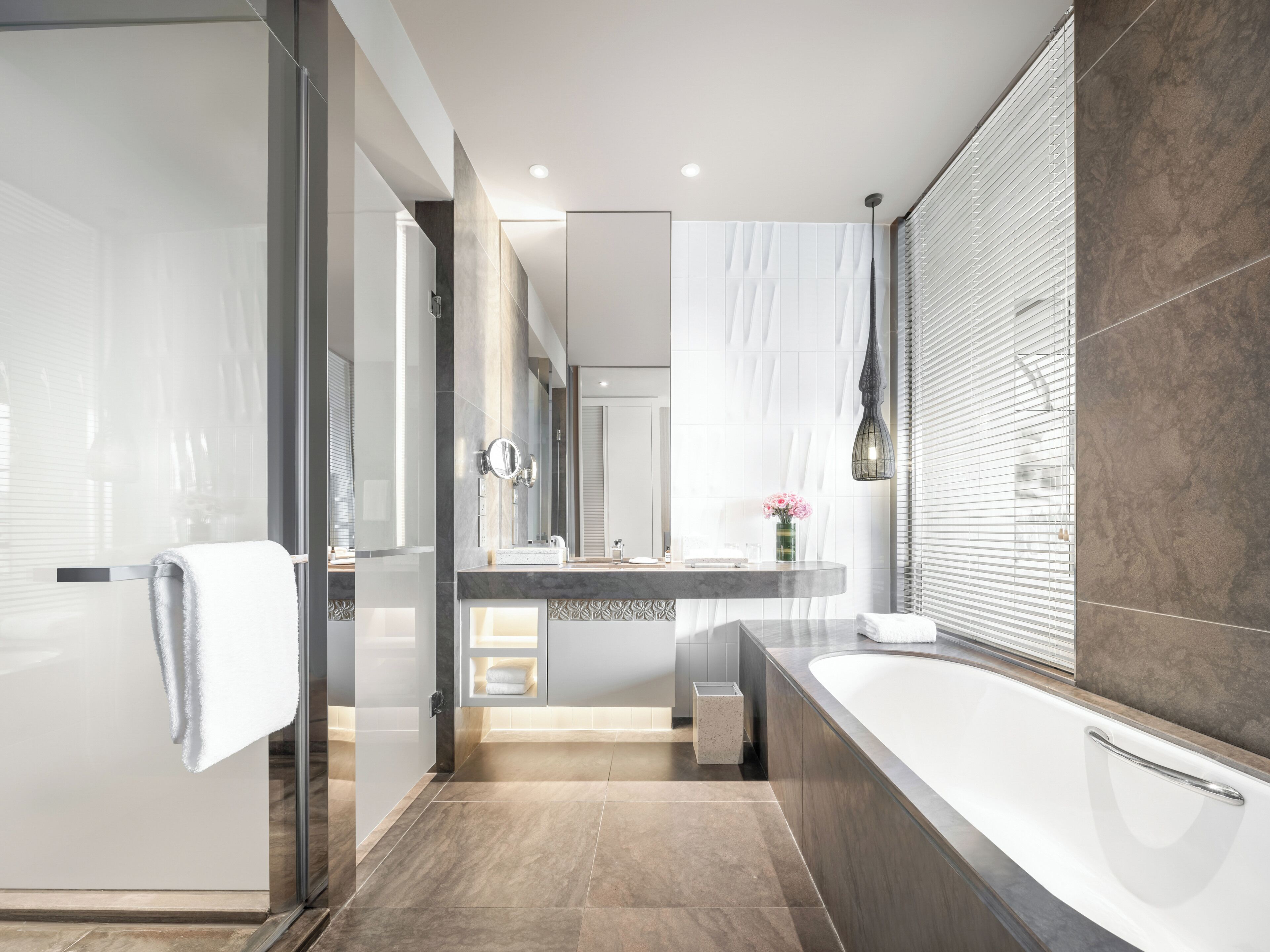 A modern bathroom with a glass shower enclosure, a large bathtub, and a vanity with a mirror.