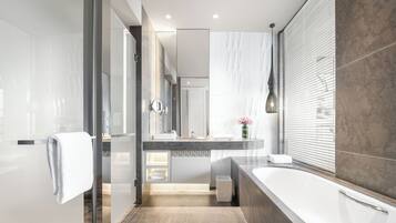A modern bathroom with a glass shower enclosure, a large bathtub, and a vanity with a mirror.