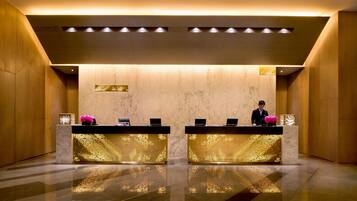 A reception area with two reception desks, a marble wall, and a polished floor.