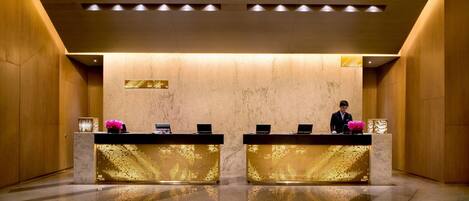 A reception area with two reception desks, a marble wall, and a polished floor.