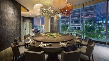 A modern conference room with a round table, chairs, and decorative hanging lamps.