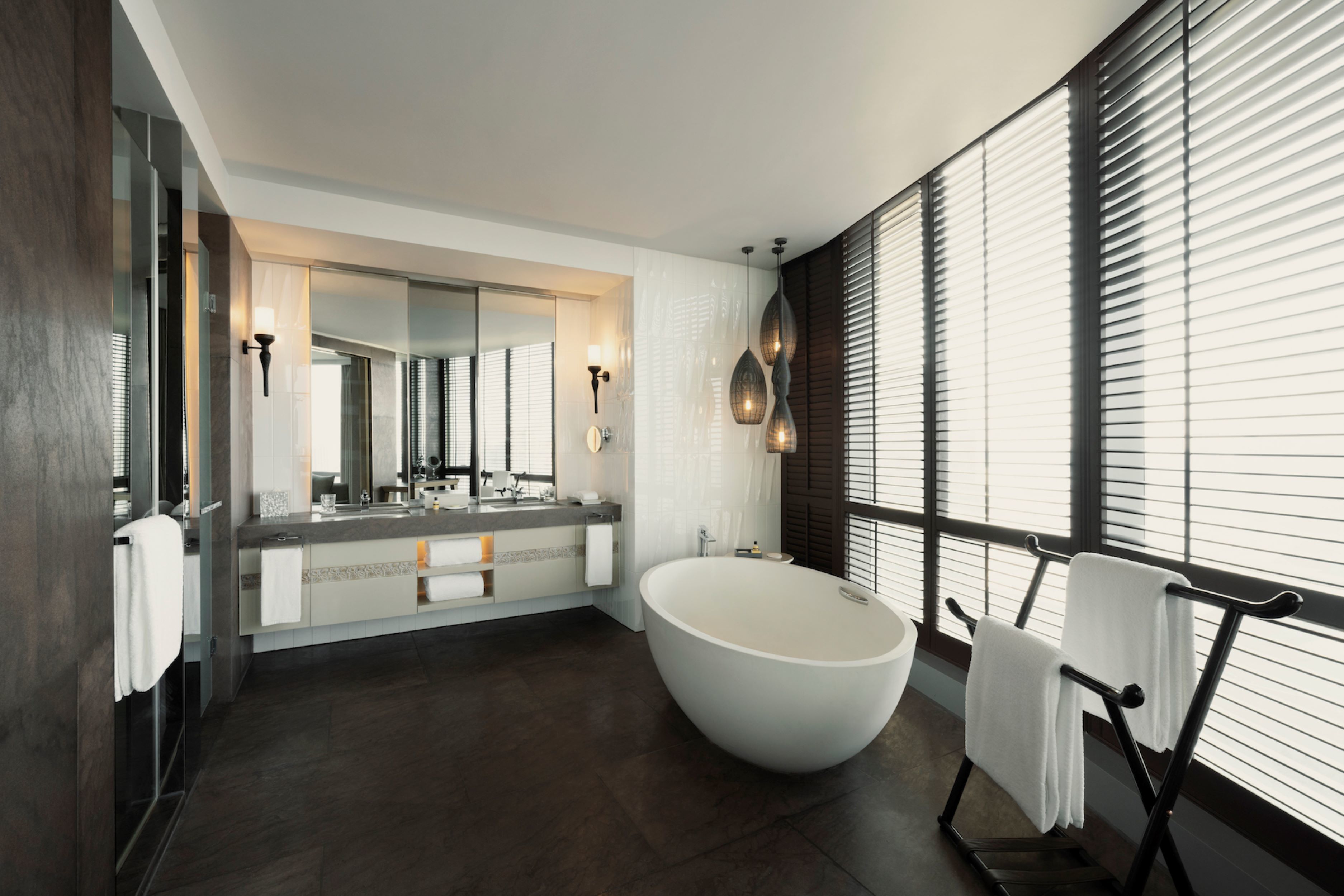 Une salle de bain moderne avec une baignoire sur pieds, un grand miroir et un meuble-lavabo doté d’un plan de travail.