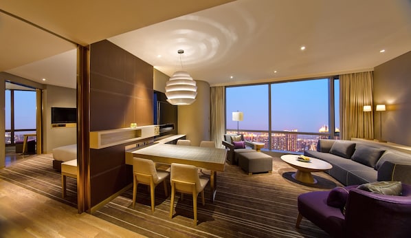 A modern hotel room with a dining area, a sofa, and a view of the cityscape. - Hyatt Regency Suzhou (Suzhou)