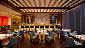 A modern bar area with a long counter, multiple seating options, and a patterned wall. - Hyatt Regency Suzhou (Suzhou)