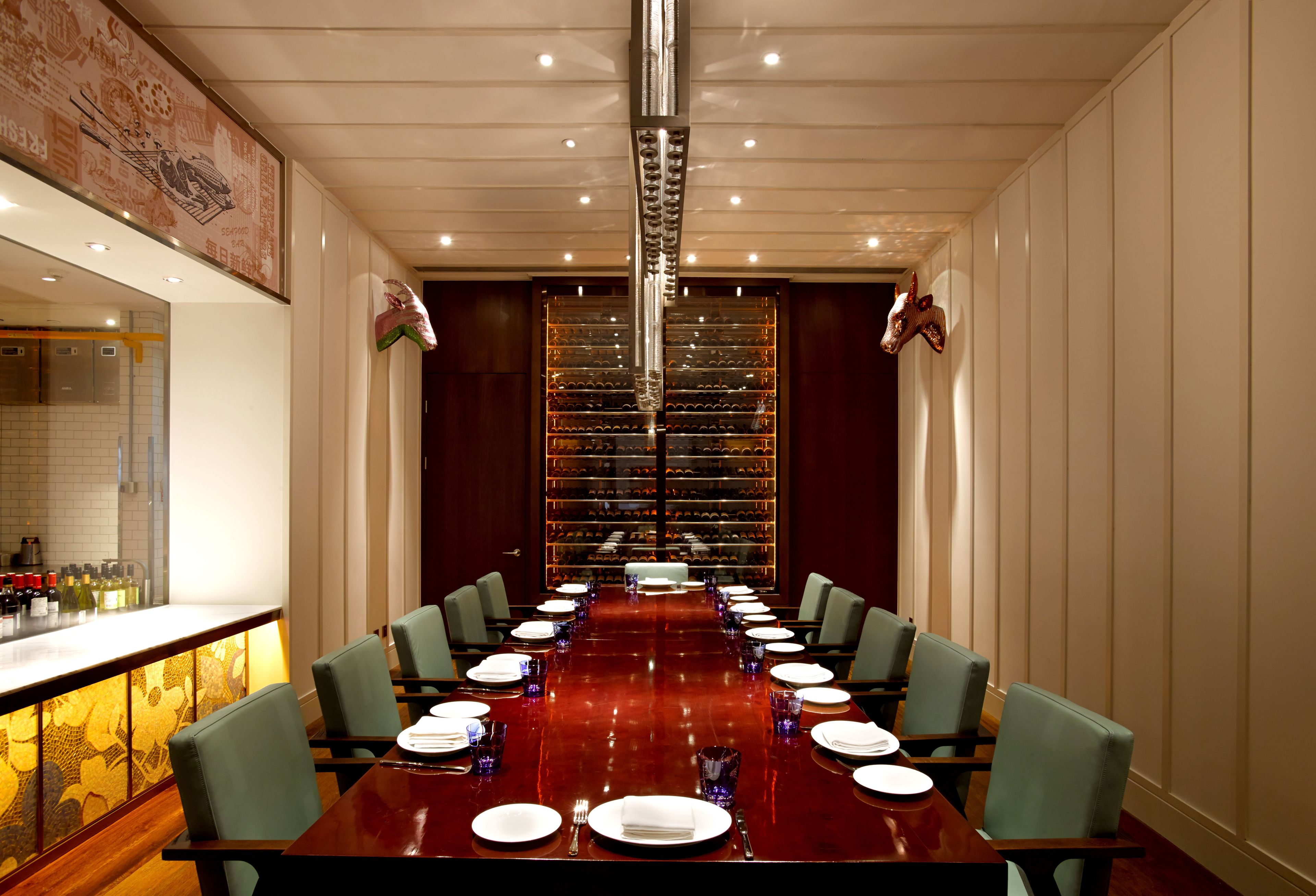 Una sala de conferencias con una larga mesa, sillas y una estantería para vinos al fondo.