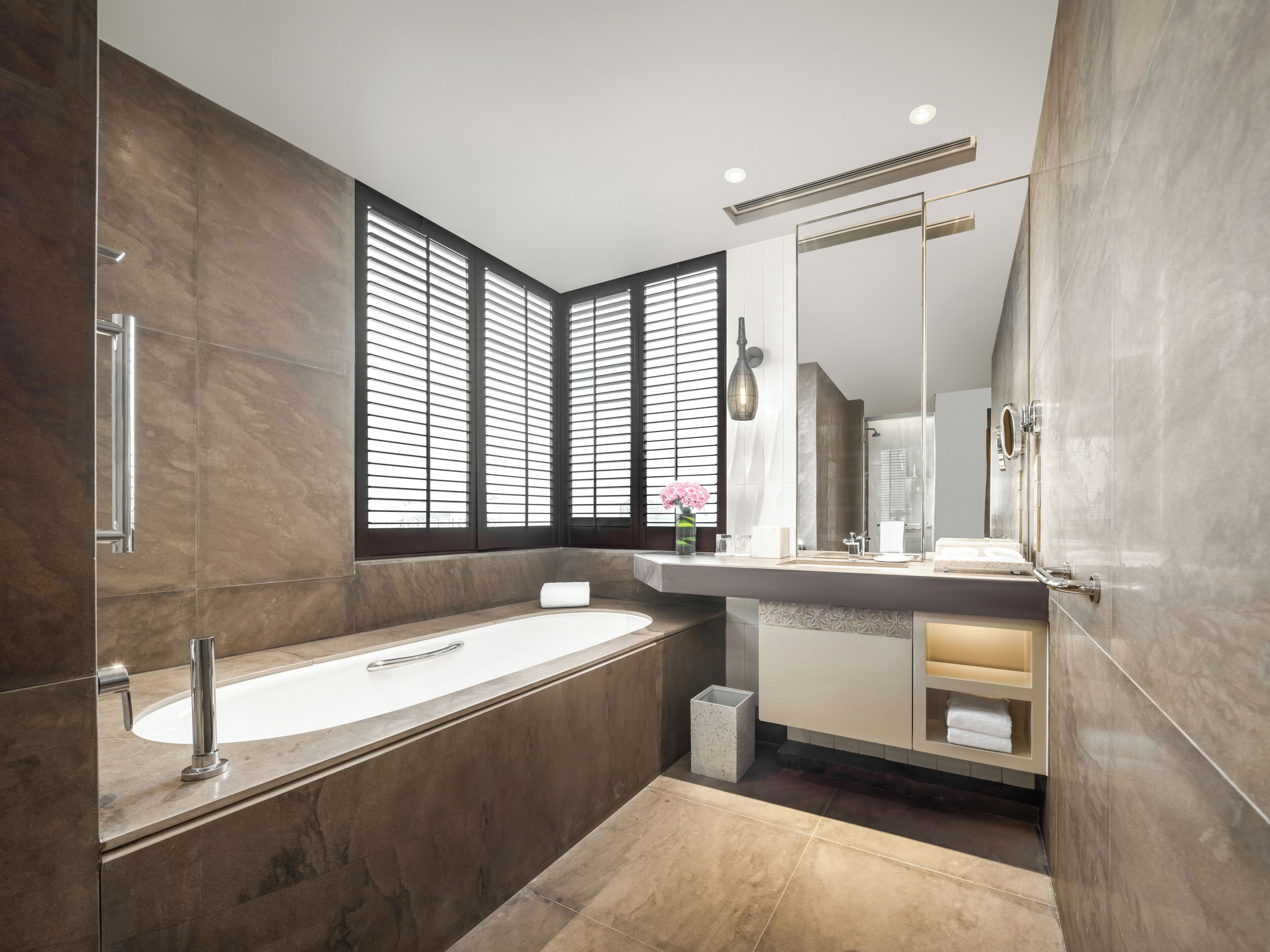 Un baño moderno con una bañera independiente, un espejo grande y un tocador con lavabo.