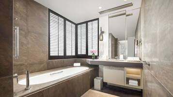 Un baño moderno con una bañera independiente, un espejo grande y un tocador con lavabo.
