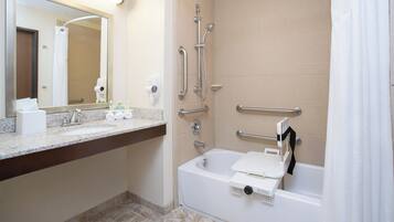 A bathroom with a sink, mirror, towel rack, shower with grab bars, and a bathtub.