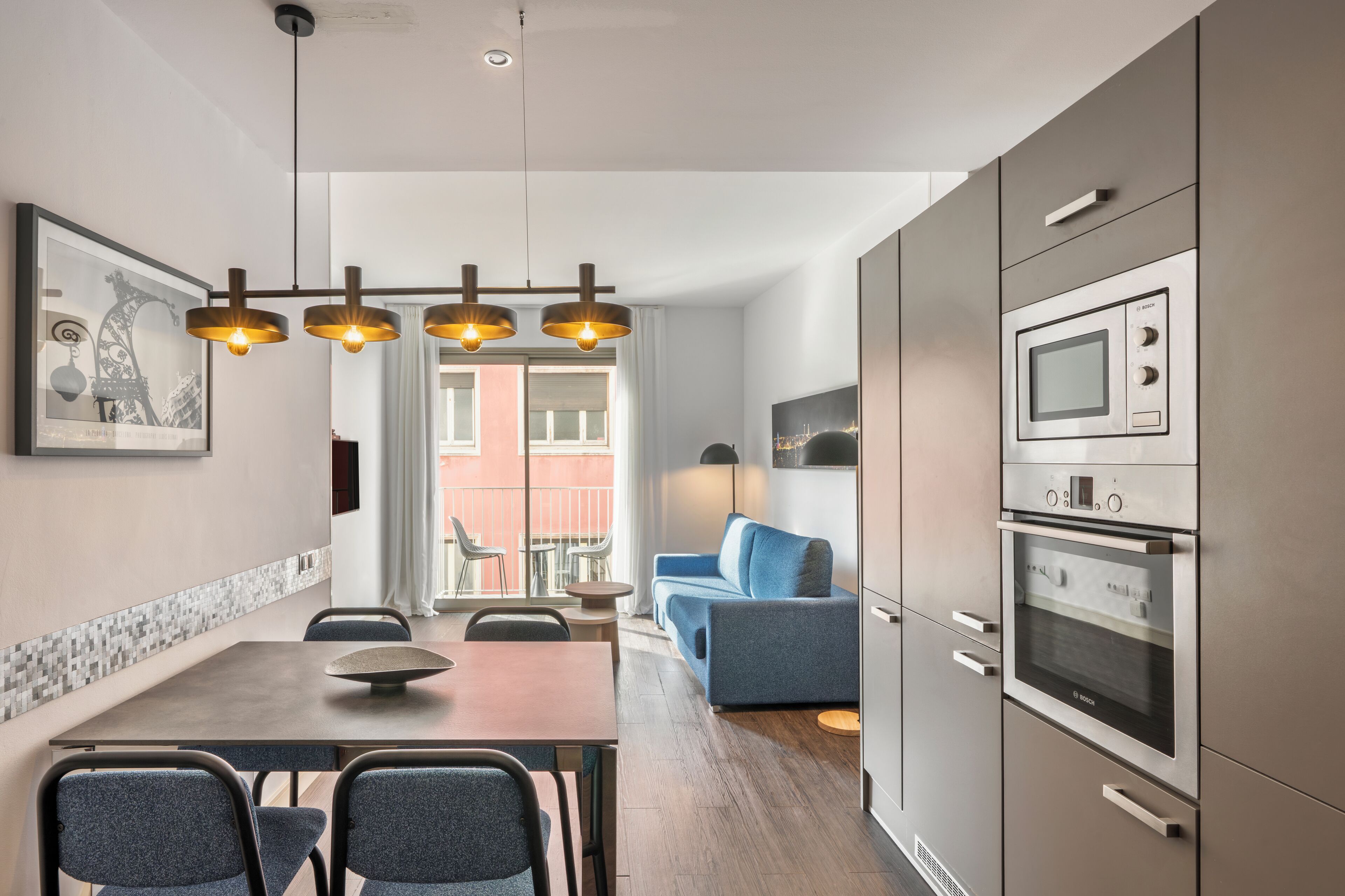 Una cucina moderna con zona pranzo, un divano blu e un'ampia finestra.